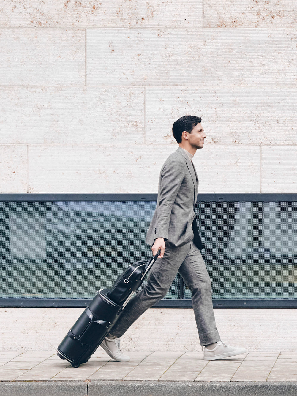 male model walking with f38 black carry-on luggage in italian leather black leather schwarzes leder
